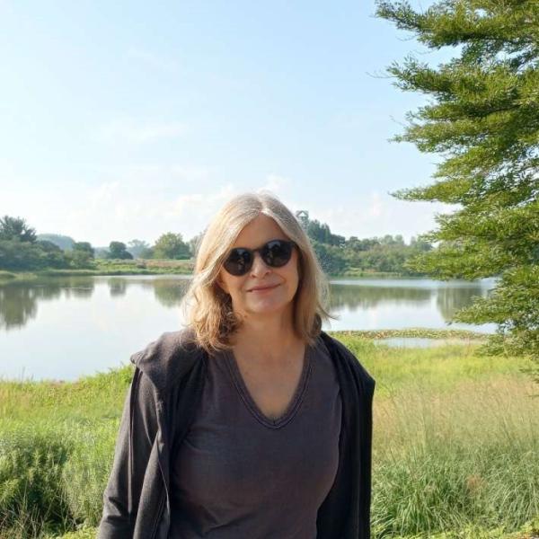 Photo of woman in sunglasses standing in front of a lake.